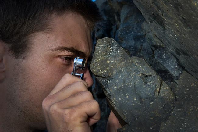 A student examining a rock through a hand lens in St. John's, Newfoundland